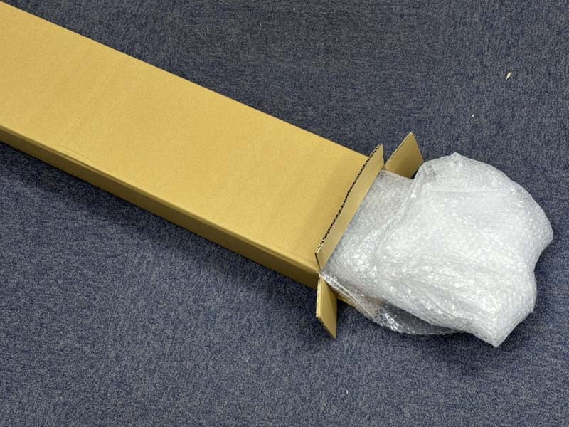 緩衝シートで保護されたLMGが細長い段ボール箱に入っている